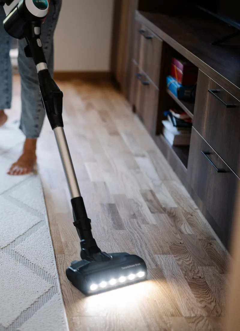 Vacuuming a patterned rug in a bright living room