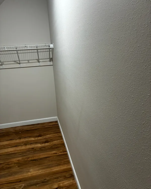 Empty walk-in closet with a wire shelf and a wood-look floor